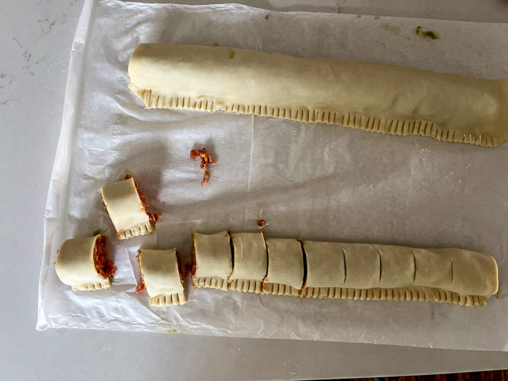 sausage rolls cut up on parchment paper