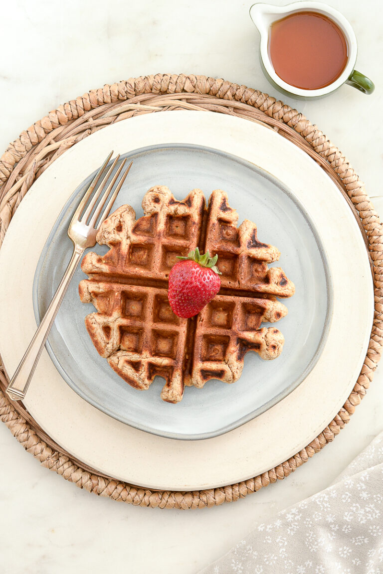Overhead shot of sourdough whole grain waffles with syrup, fork and strawberry